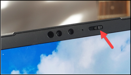 Camera snapshot of the upper bezel of a laptop monitor camera and switch with an arrow pointing to the switch